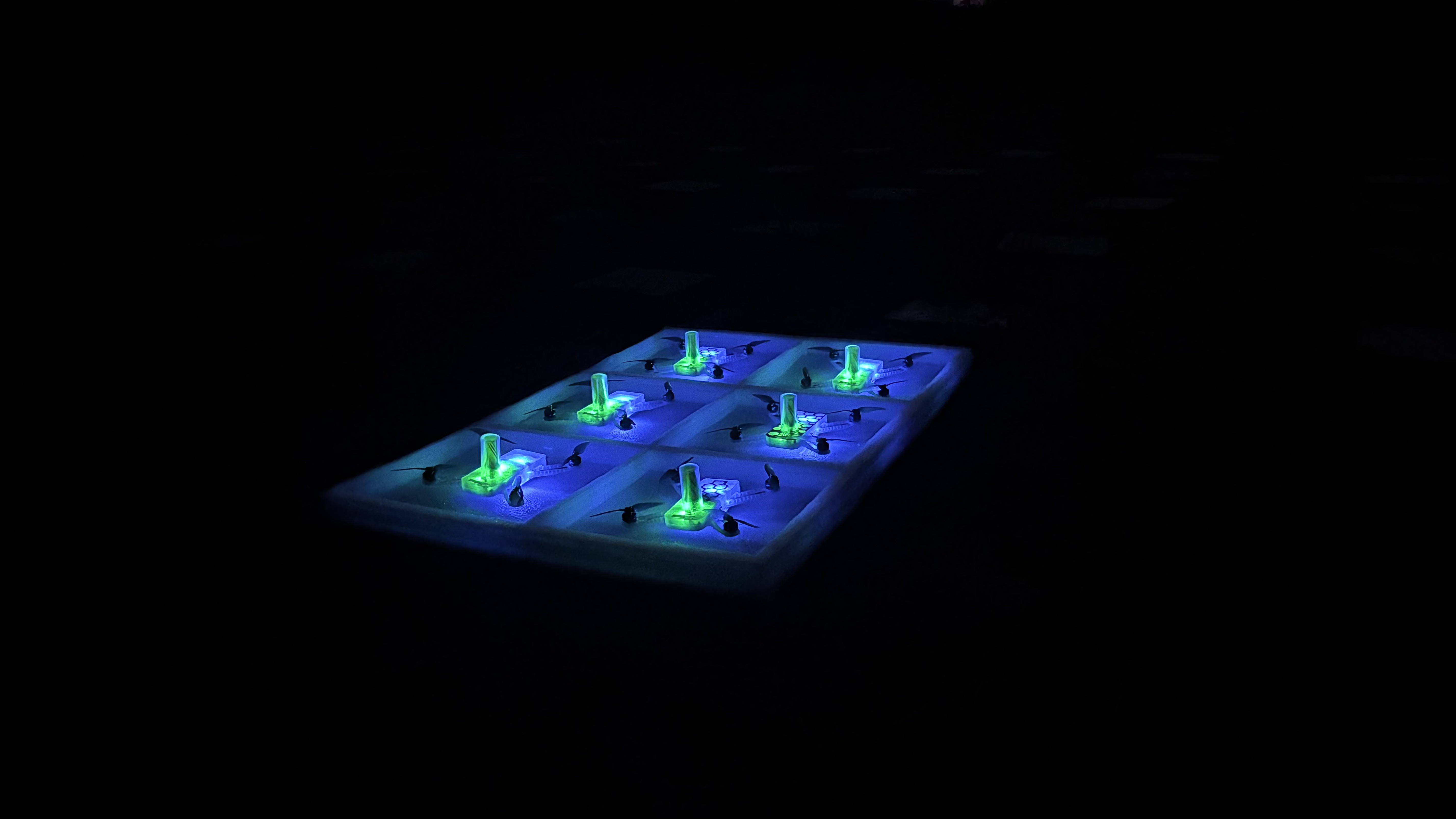 Aerostar drones glowing green and blue inside launch boxes at night